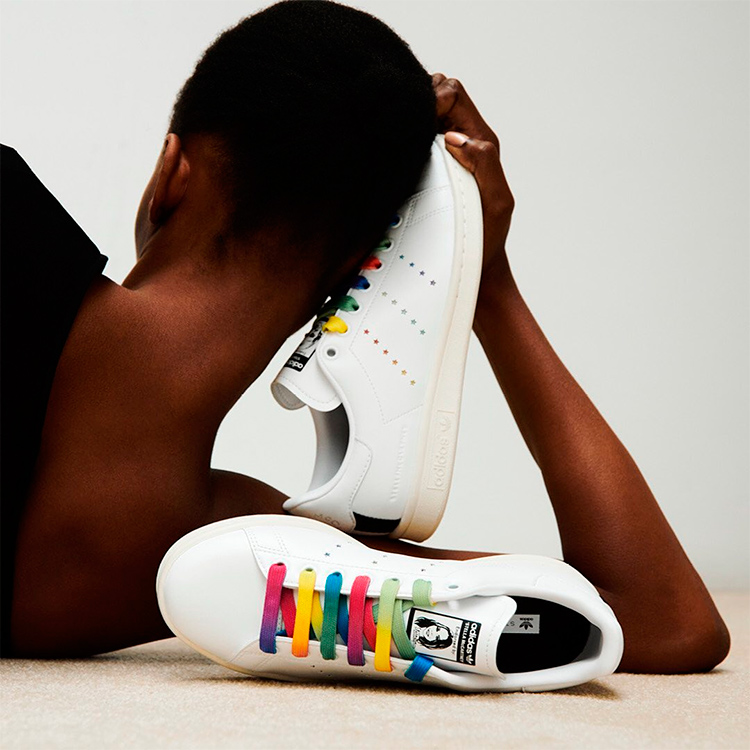 Sneakers sostenibili bianche con lacci colorati appoggiati al collo di una donna 