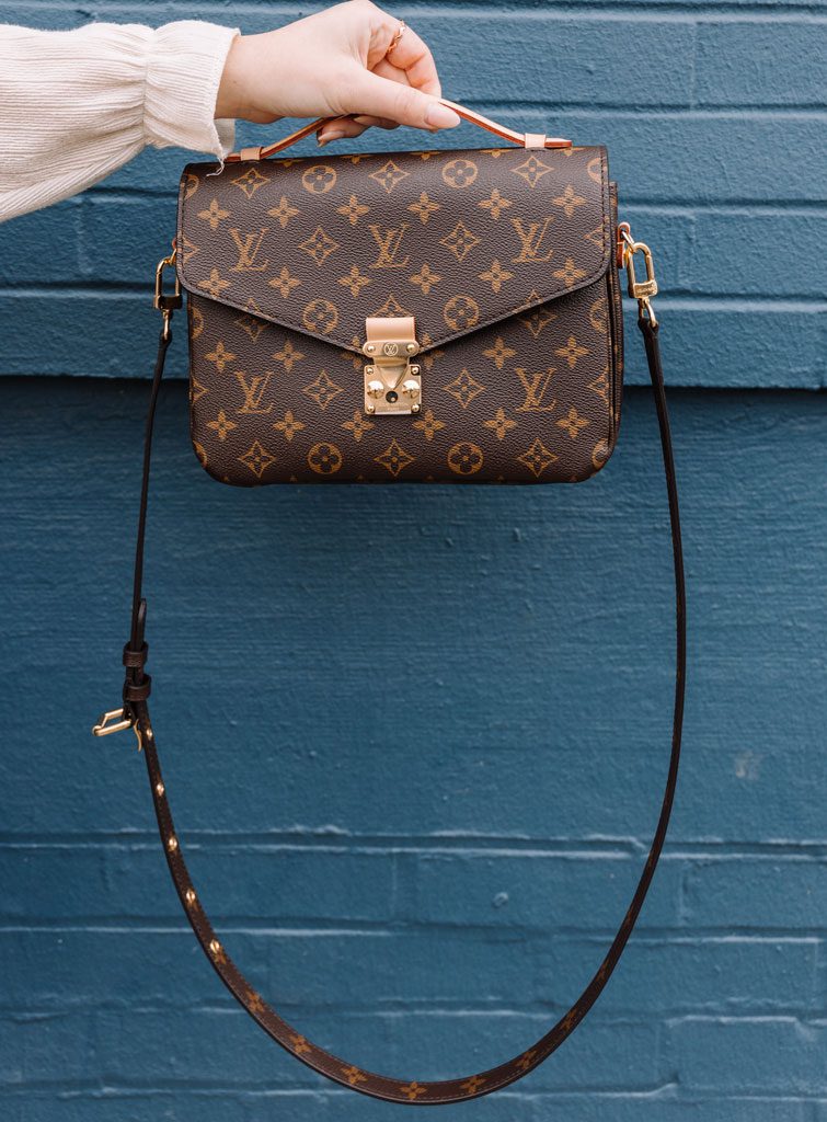 Foto di una originale borsa Louis Vuitton piccola e con tracolla sorretta dalla mano di una ragazza