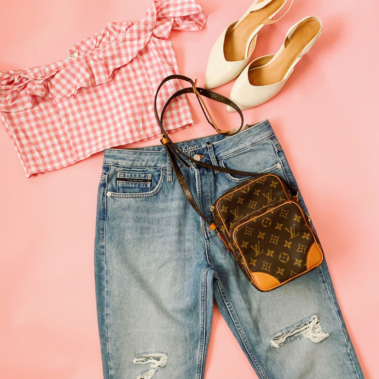 Outfit creato con dei jeans, maglietta, tacco e una originale borsa Louis Vuitton su uno sfondo rosa barbie