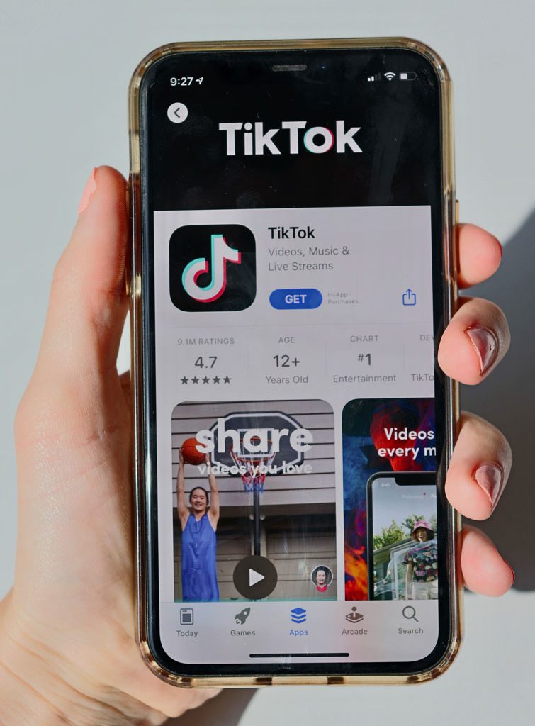 schermo di un iphone tenuto nella mano di qualcuno che mostra l’app store in cui sta scaricando l’app tik tok