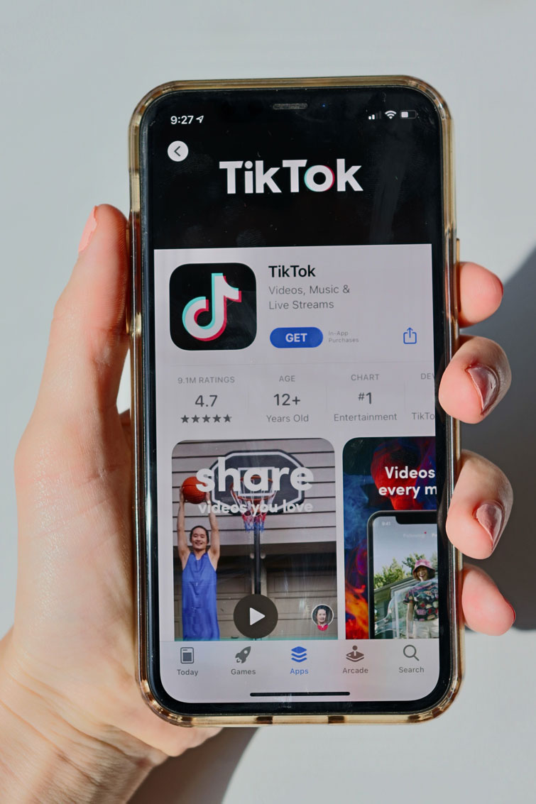 schermo di un iphone tenuto nella mano di qualcuno che mostra l’app store in cui sta scaricando l’app tik tok
