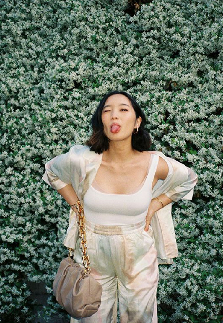Jenn Im, una tra le influencer più seguite al mondo, mentre fa la linguaccia davanti ad una parete di fiori