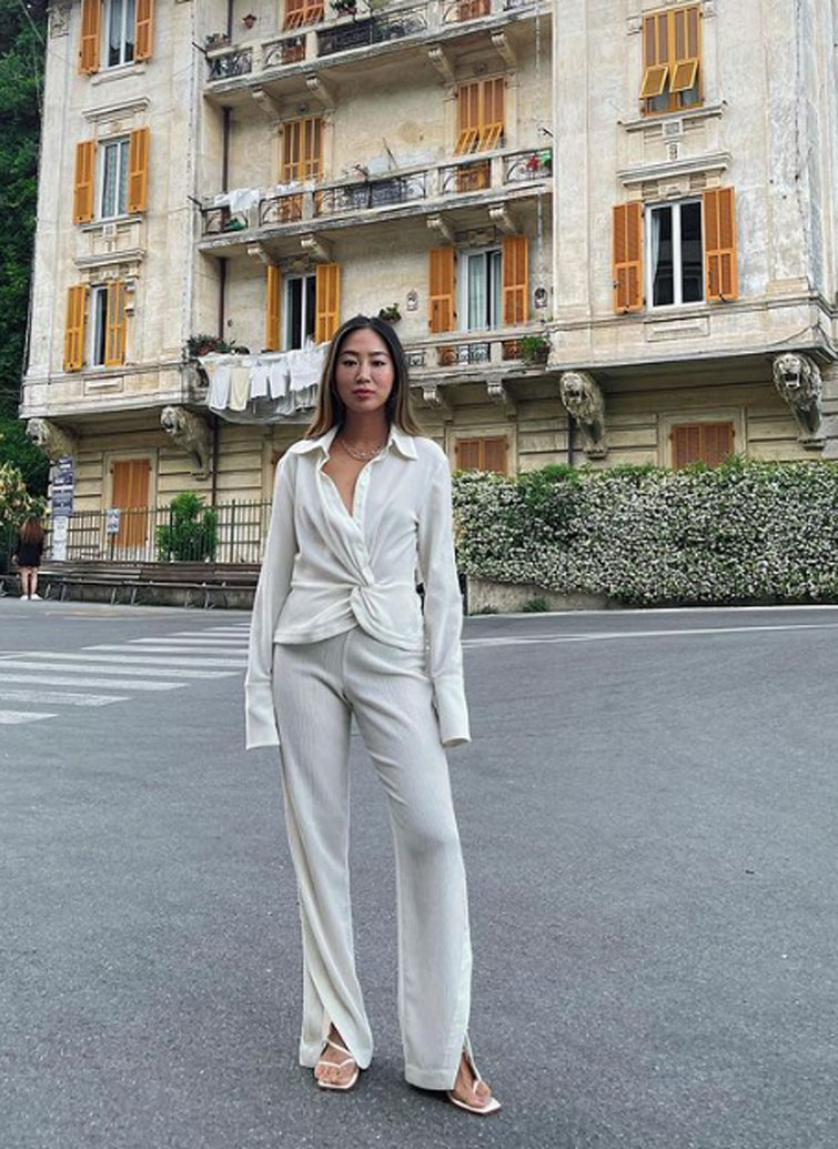 Aimee Song, una delle influencer con più follower al mondo, in posa con un completo bianco in una strada di Portofino