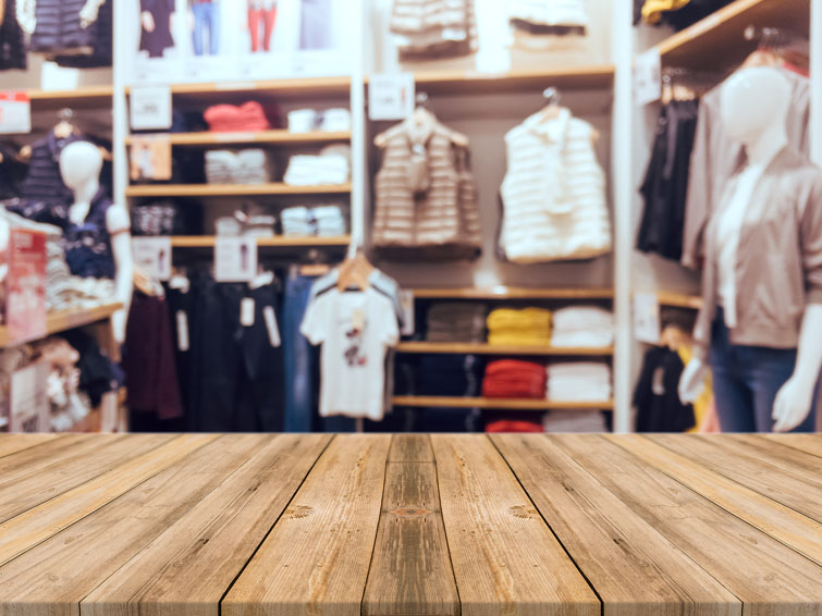tavolo di legno in primo piano con sfondo sfogato di un mercatino di abbigliamento usato a verona