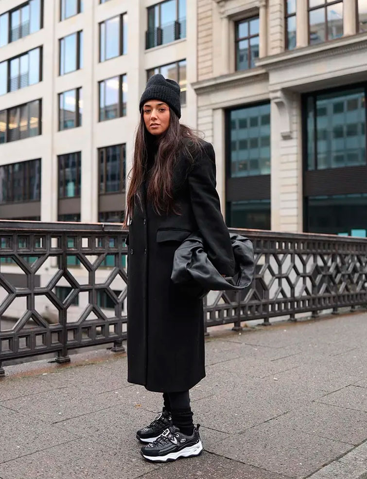 una influencer in posa con un outfit interamente dalle tonalità scure che indossa delle scarpe nere, tra le sneakers da donna 2022 di tendenza 