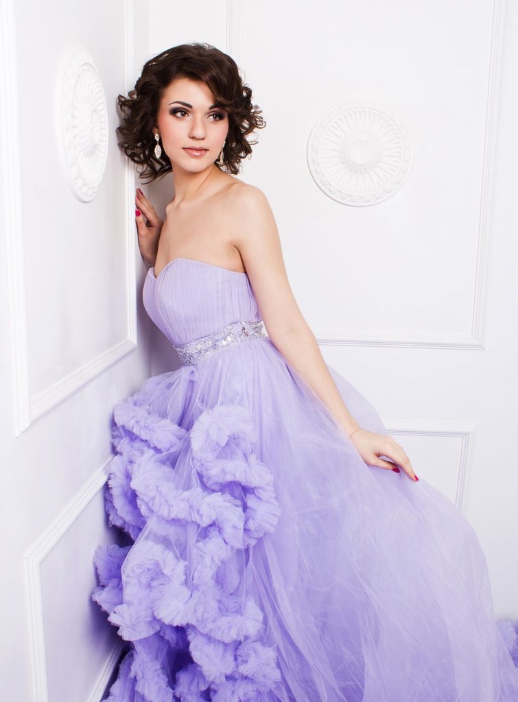 ragazza elegante in posa che indossa un vestito lilla da matrimonio acquistato in un negozio di noleggio abiti di lusso
